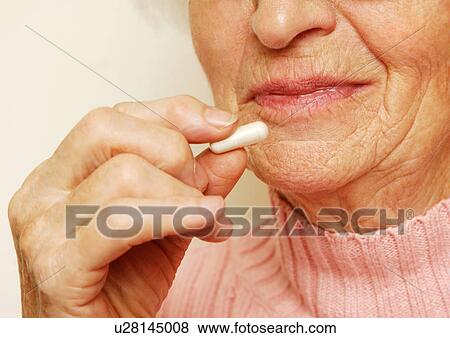Stock Photo - Close-up of an elderly woman having her medicine.. Fotosearch