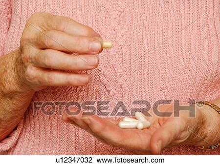 Stock Image - Midsection of a woman holding some capsules.. Fotosearch