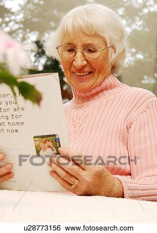 Stock Photograph - Portrait of a woman looking at a greeting card.. Fotosearch