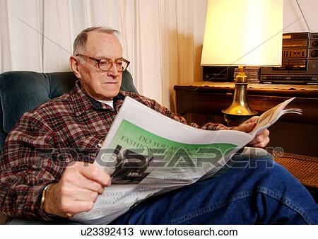 Stock Image - Portrait of an elderly man reading a newspaper.. Fotosearch