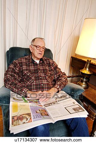 Stock Photo - Portrait of an elderly man reading a newspaper.. Fotosearch