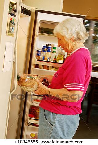 Stock Photography - Profile of a woman standing near a refrigerator.. Fotosearch