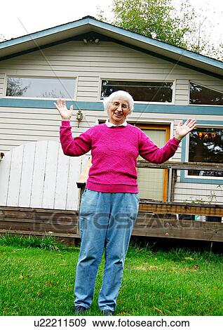 Stock Photo - View of an elderly woman against her house.. Fotosearch