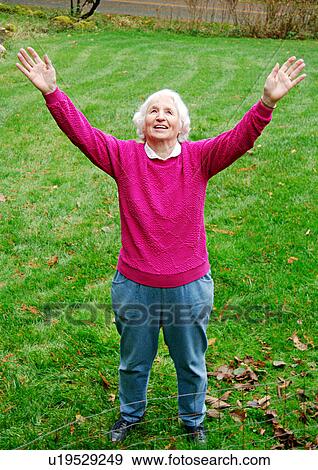 Stock Photo - View of en elderly woman with raised hands.. Fotosearch