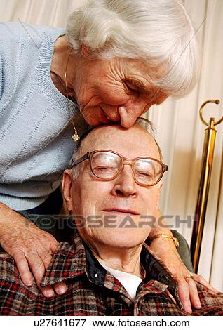An elderly woman kissing her husbands forehead. View Large Photo Image Stock Photo - An elderly woman kissing her husbands forehead.. Fotosearch