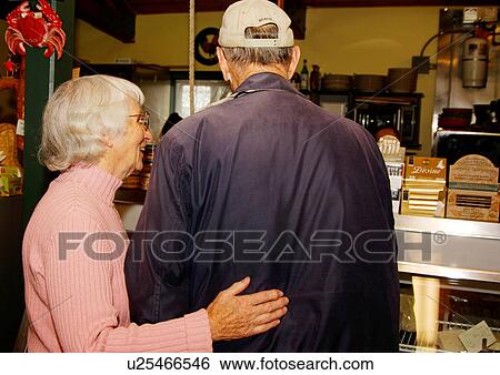Stock Photograph - Rear view of an elderly couple at a supermarket.. Fotosearch
