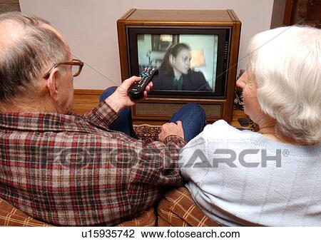 Stock Image - View of an elderly couple enjoying a television show.. Fotosearch