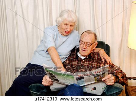 Stock Photo - View of an elderly couple reading a newspaper.. Fotosearch