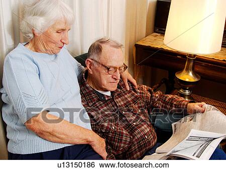 Stock Photograph - View of an elderly couple reading a newspaper.. Fotosearch