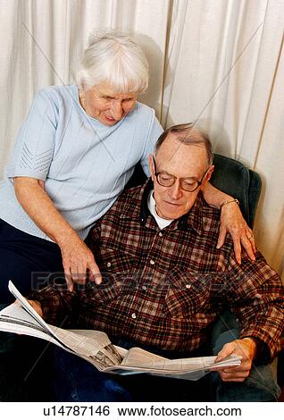Stock Photograph - View of an elderly couple reading a newspaper.. Fotosearch