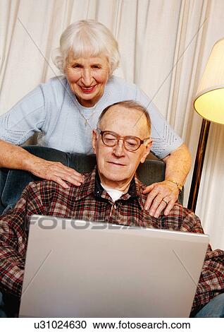 View of an elderly couple surfing on their laptop. View Large Photo Image Stock Image - View of an elderly couple surfing on their laptop.. Fotosearch