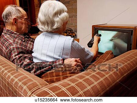 View of an elderly couple watching television. View Large Photo Image Picture - View of an elderly couple watching television.. Fotosearch