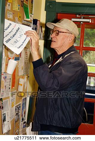 View of an elderly man checking out a message on a notice board. View Large Photo Image Stock Image - View of an elderly man checking out a message on a notice board.. Fotosearch