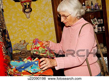 View of an elderly woman checking out the displayed products. View Large Photo Image Stock Photo - View of an elderly woman checking out the displayed products.. Fotosearch