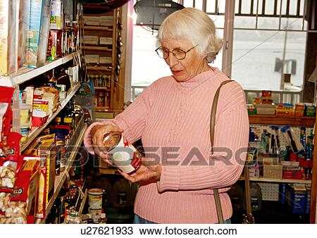 View of an elderly woman looking at a can in a supermarket View Large Photo Image Stock Image - View of an elderly woman looking at a can in a supermarket. Fotosearch