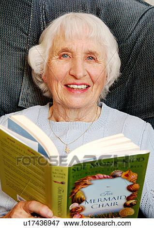 Stock Photo - View of an elderly woman reading a book.. Fotosearch