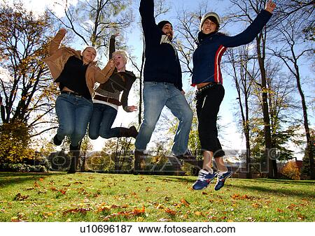 Four ecstatic friends in midair in a park. View Large Photo Image Stock Photo - Four ecstatic friends in midair in a park.. Fotosearch