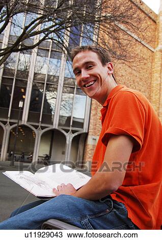 Portrait of a cheerful young man holding a book. View Large Photo Image Stock Image - Portrait of a cheerful young man holding a book.. Fotosearch
