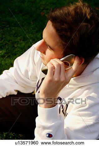 Stock Image - Portrait of a young man conversing on his cell phone.. Fotosearch