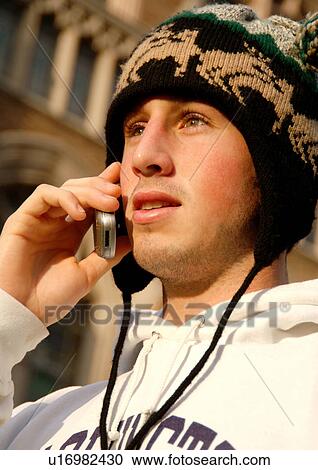 Stock Image - Portrait of a young man conversing on his cell phone.. Fotosearch