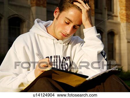 Picture - Portrait of a young man engrossed in a book.. Fotosearch