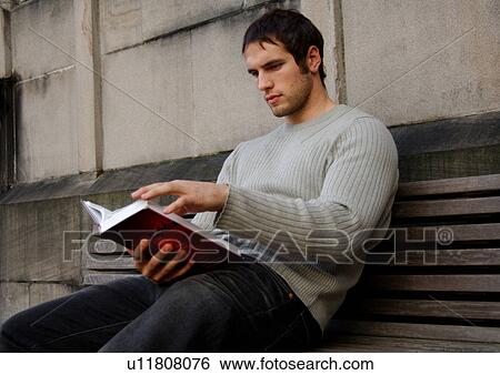 Stock Photograph - Portrait of a young man engrossed in a book.. Fotosearch