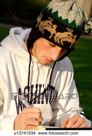 Picture - Portrait of a young man writing in a book.. Fotosearch