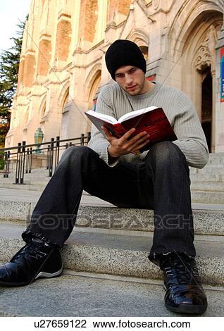 View of a young man engrossed in a book. View Large Photo Image Stock Image - View of a young man engrossed in a book.. Fotosearch