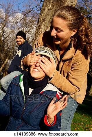 View of a young woman playfully shutting her friends eyes. View Large Photo Image Stock Photograph - View of a young woman playfully shutting her friends eyes.. Fotosearch