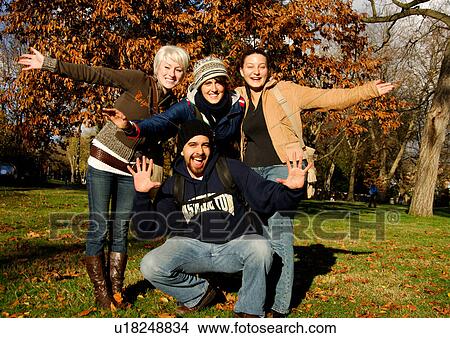 View of four ecstatic friends posing against the camera. View Large Photo Image Picture - View of four ecstatic friends posing against the camera.. Fotosearch