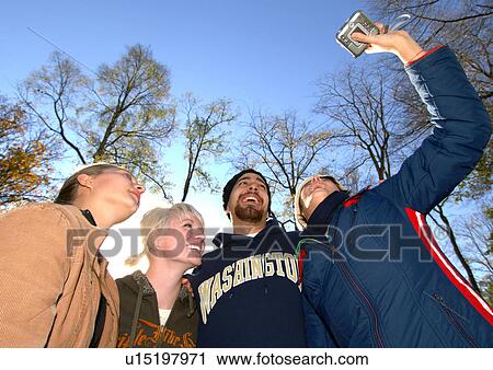 Stock Image - View of four people recording themselves on a camcorder.. Fotosearch