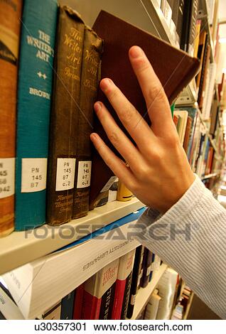 Stock Image - A person picking a book from a library.. Fotosearch