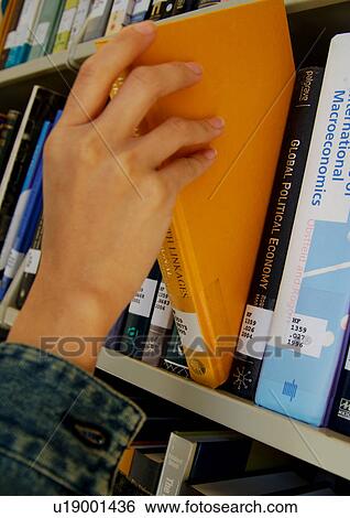 Stock Photograph - A person picking a book from a library.. Fotosearch