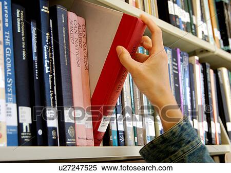 Stock Photography - A person picking a book from a library.. Fotosearch