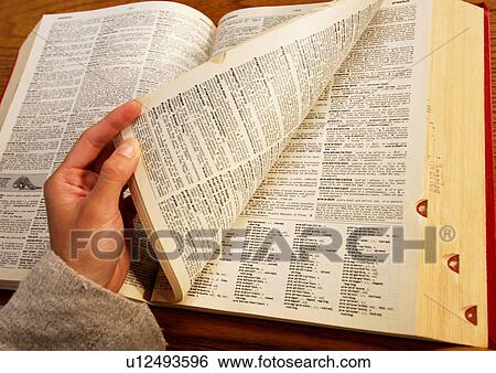 Stock Photograph - A student is browsing through a huge book.. Fotosearch