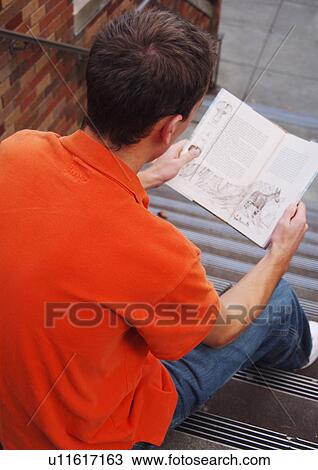A young man engrossed in his book. View Large Photo Image Stock Image - A young man engrossed in his book.. Fotosearch
