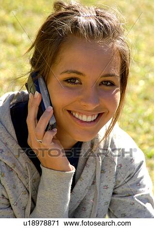 Stock Image - A young woman talking on her cell phone.. Fotosearch