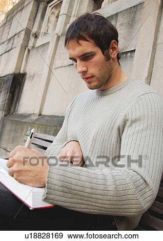 Portrait of a young man writing in a book. View Large Photo Image Stock Photo - Portrait of a young man writing in a book.. Fotosearch