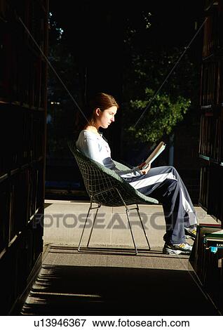 Profile of a young woman reading a book in a library. View Large Photo Image Stock Photo - Profile of a young woman reading a book in a library.. Fotosearch