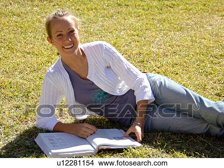Picture - View of a young woman lying on a lawn.. Fotosearch