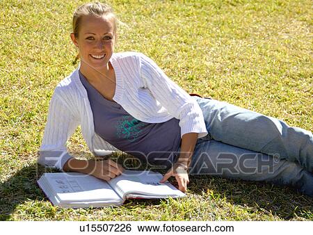 View of a young woman lying on a lawn. View Large Photo Image Stock Photograph - View of a young woman lying on a lawn.. Fotosearch