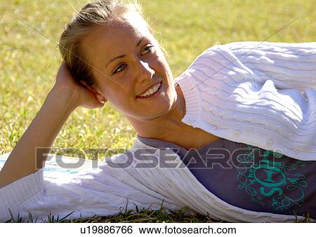 Stock Photograph - View of a young woman lying on a lawn.. Fotosearch