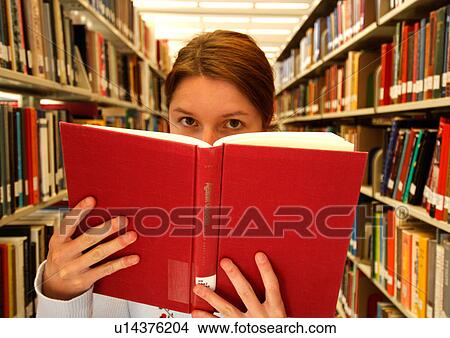 View of a young woman reading a book in a library. View Large Photo Image Picture - View of a young woman reading a book in a library.. Fotosearch