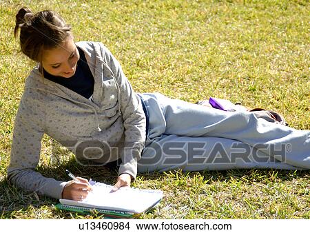 View of a young woman studying on a lawn. View Large Photo Image Picture - View of a young woman studying on a lawn.. Fotosearch