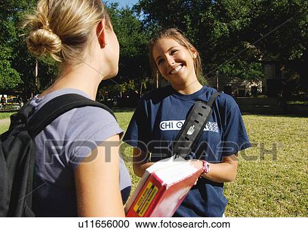 Stock Image - View of two young women engaged in a conversation.. Fotosearch