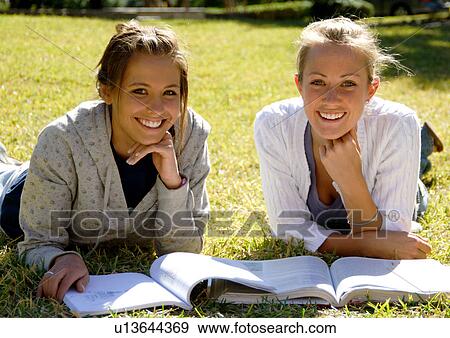View of two young women reading books on a lawn. View Large Photo Image Stock Photo - View of two young women reading books on a lawn.. Fotosearch