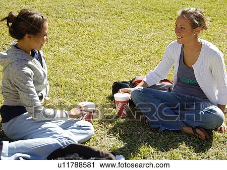 View of two young women relaxing on a lawn. View Large Photo Image Stock Image - View of two young women relaxing on a lawn.. Fotosearch