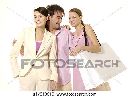 Stock Photo - Front view of young shoppers posing with their carrier bags.. Fotosearch
