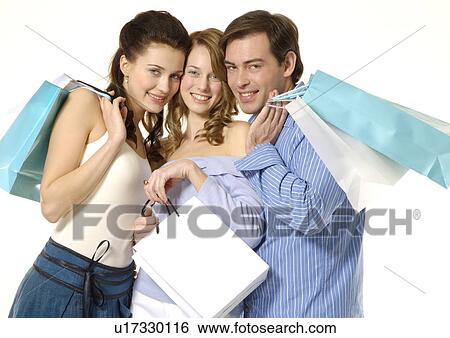 Stock Photograph - Front view of young shoppers posing with their carrier bags.. Fotosearch