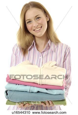 Stock Image - Portrait of a cheerful woman holding folded apparels.. Fotosearch